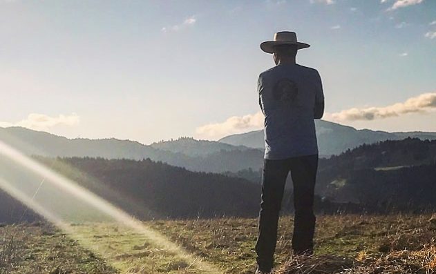 man in hat looking out on open land